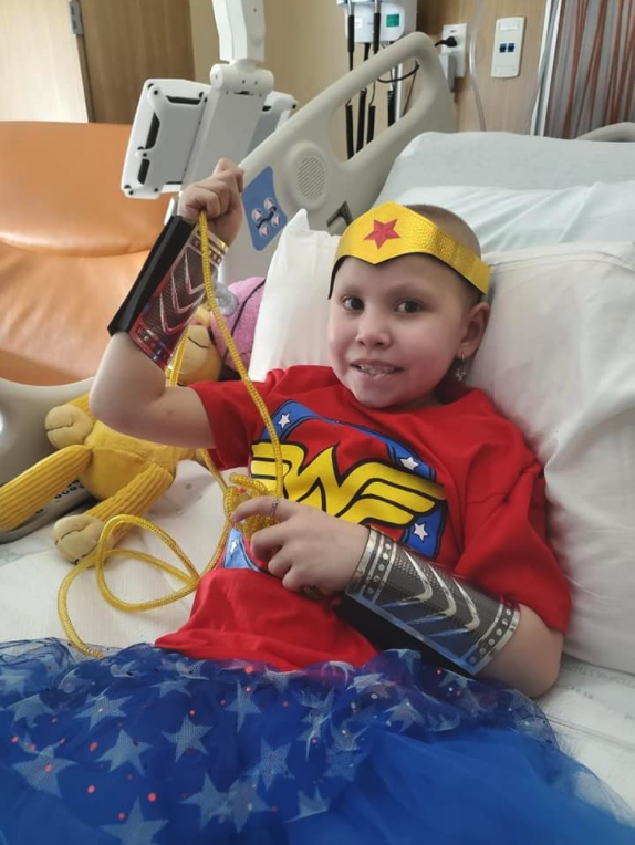 Cienna wearing Wonder Woman tshirt and headband while in hospital bed