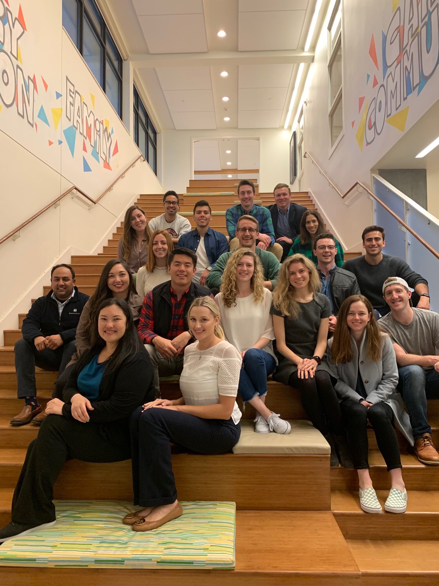 a group of twenty and thirty year old young professionals pose on the main stairway at Family House after volunteering